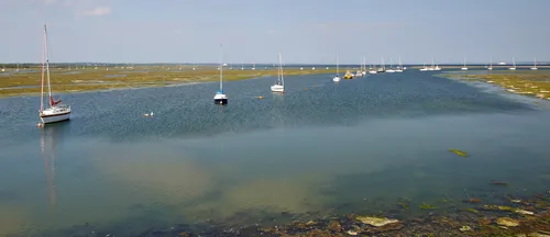 Boats anchored Milford-on-sea This is a landscape photograph taken in the afternoon during late spring, capturing a tranquil scene of boats anchored in the waters near Milford-on-sea, Dorset, United Kingdom. The image highlights a stretch of Milford Haven where small sailing boats and yachts are moored, illustrating a peaceful aspect of local transport within the region. The view encompasses the shallow tidal waters and marshes characteristic of this part of Dorset, with boats dotting the calm surface under a partly cloudy sky. The photograph was taken in the direction of the open water, with distant boats and the extensive marshlands forming the backdrop, presenting Milford-on-sea as a notable coastal settlement along the southern coast of the United Kingdom.